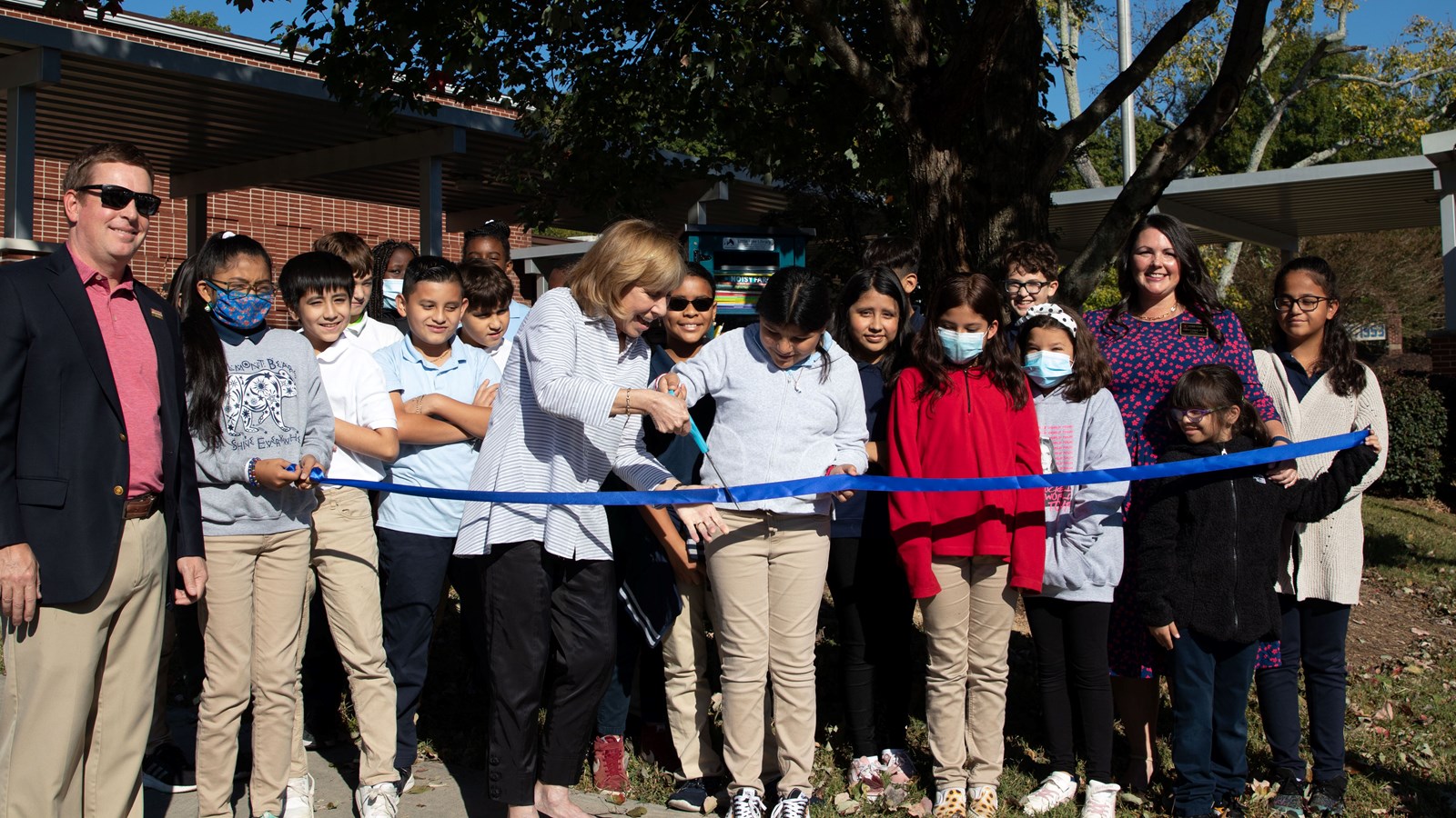 Belmont Hills Elementary School students with help of community members help cut the ribbon on the school’s new Little Free Library.